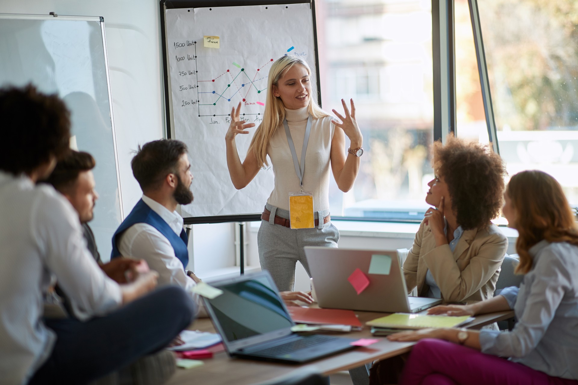 young blonde female caucasian explains business plan to other coworkers. business, passion, presentation, excitement